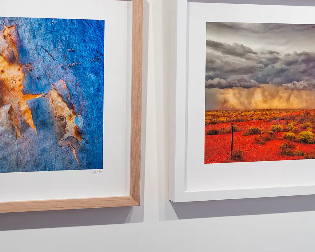 Two framed prints hanging on a wall. One with white frame the other with Tasmanian oak frame.