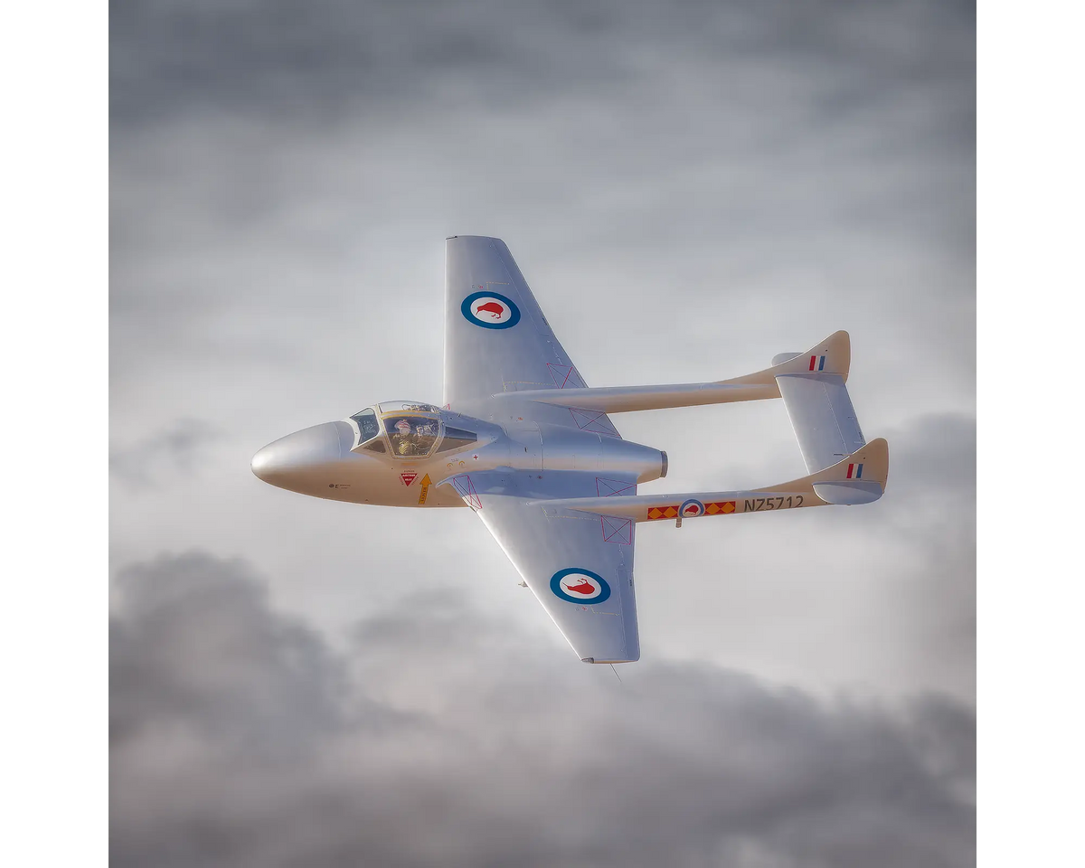 De Havilland Vampire in Royal New Zealand Air Force colours , flying against backdrop of clouds.