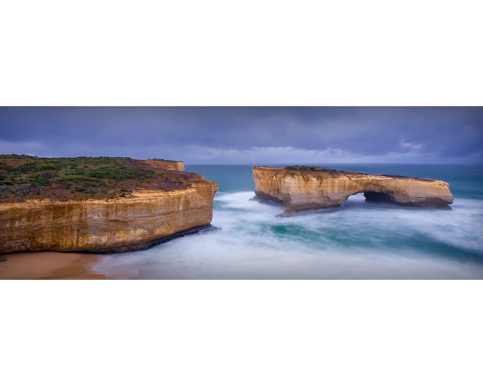 Rough waters and stormy skies over London Arch, Port Campbell National Park, Victoria. 