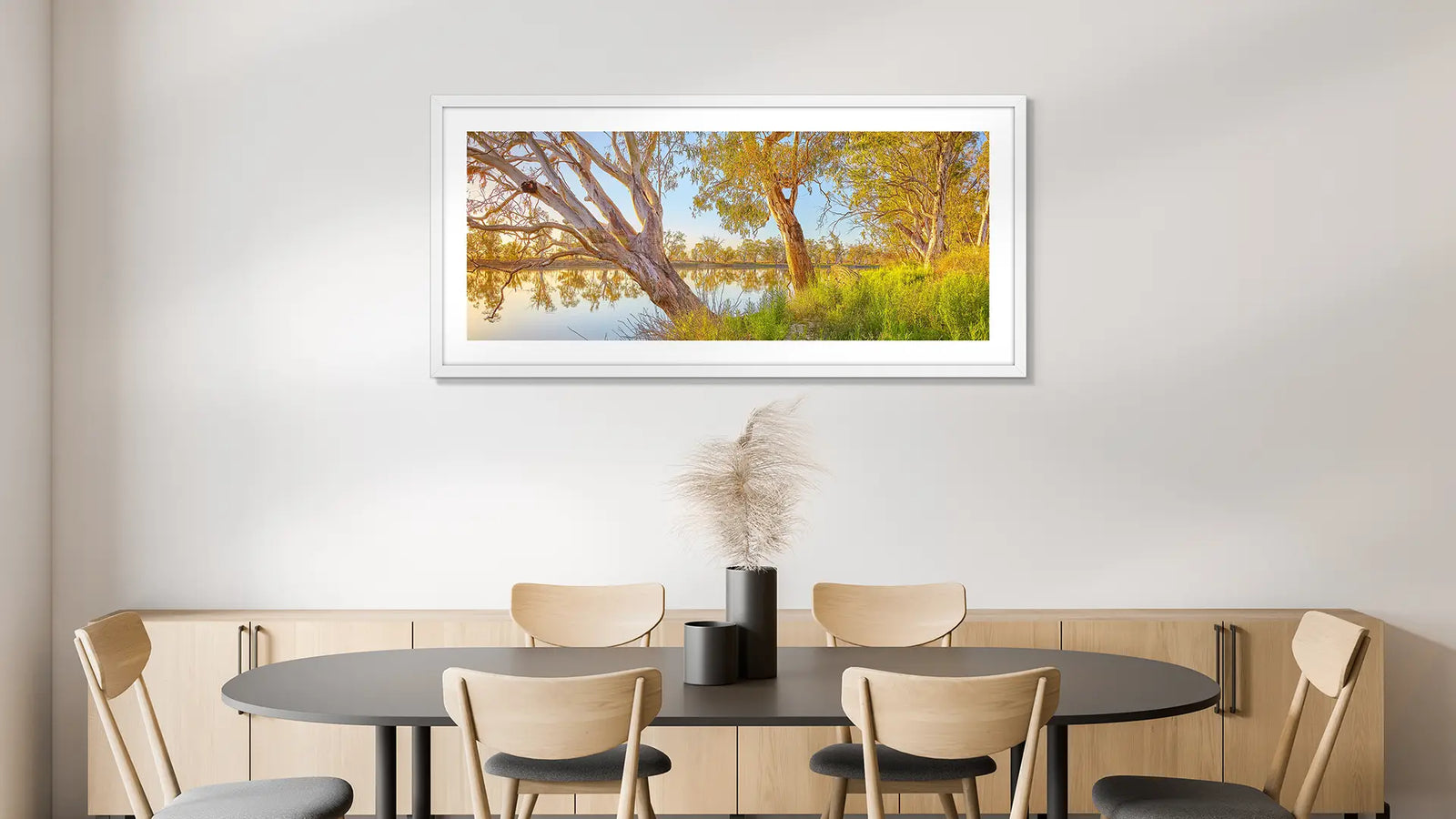 Dining room with a round table and chairs, featuring a framed landscape print on the wall.