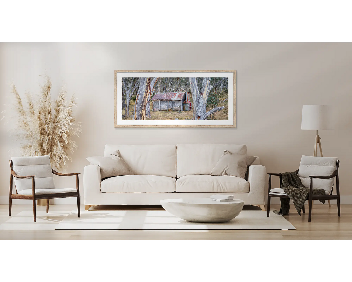 Abode Among the Gum Trees. Wall art print with timber frame of Cascade Hut, Kosciuszko National Park, hung above a couch.