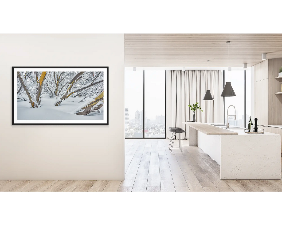 After the Storm. Wall art print of snow gums on Mount Hotham, covered in snow, framed with a black frame, and hung outside a light filled kitchen. 