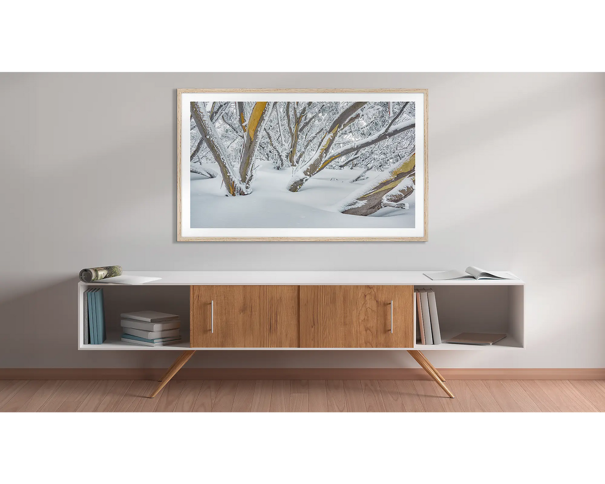 After the Storm. Wall art print of snow gums on Mount Hotham, covered in snow, framed with a Tasmanian Oak frame, and hung above a side table. 