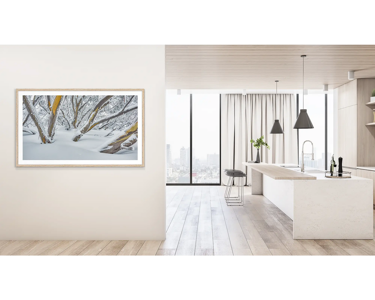 After the Storm. Wall art print of snow gums on Mount Hotham, covered in snow, framed with a Tasmanian Oak frame, and hung outside a light filled kitchen. 
