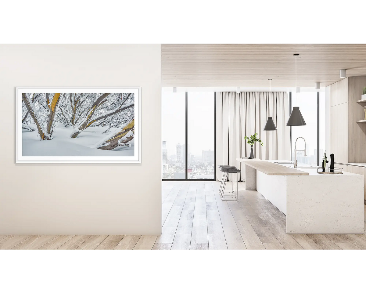 After the Storm. Wall art print of snow gums on Mount Hotham, covered in snow, framed with a white frame, and hung outside a light filled kitchen. 