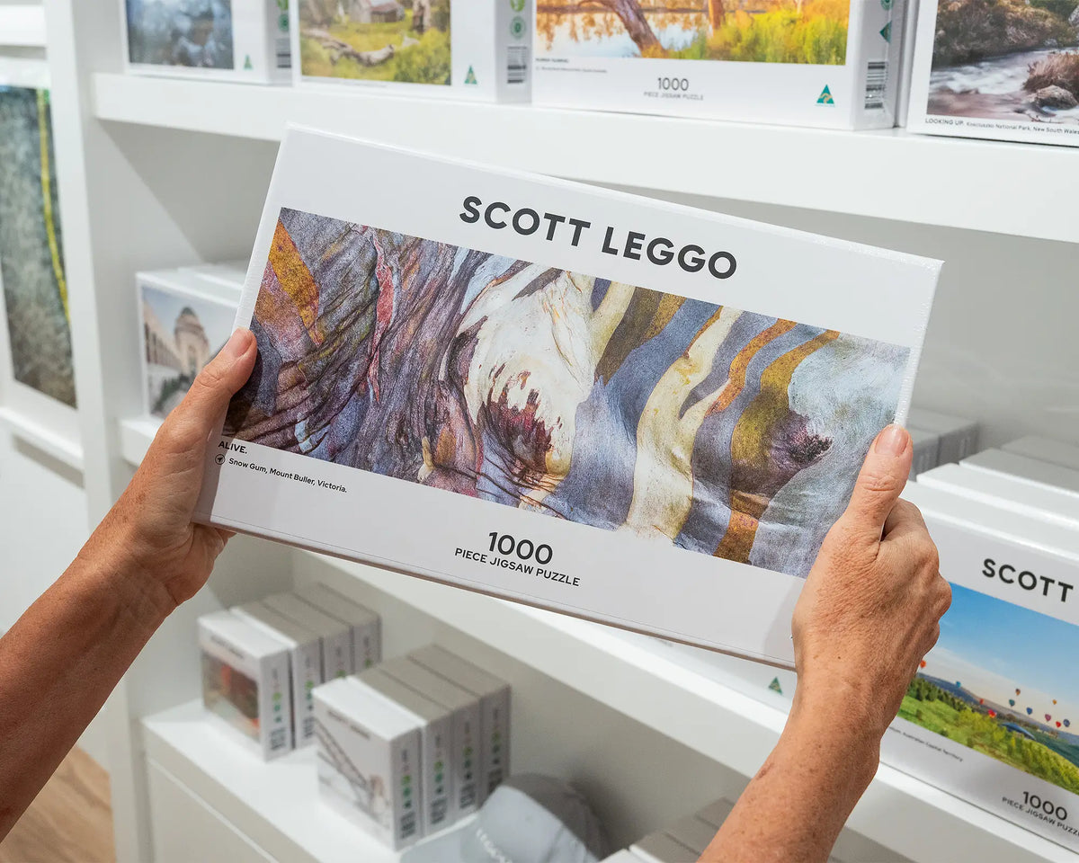 Alive. 1000 piece abstract jigsaw puzzle of colourful snow gum patterns, held in hands.