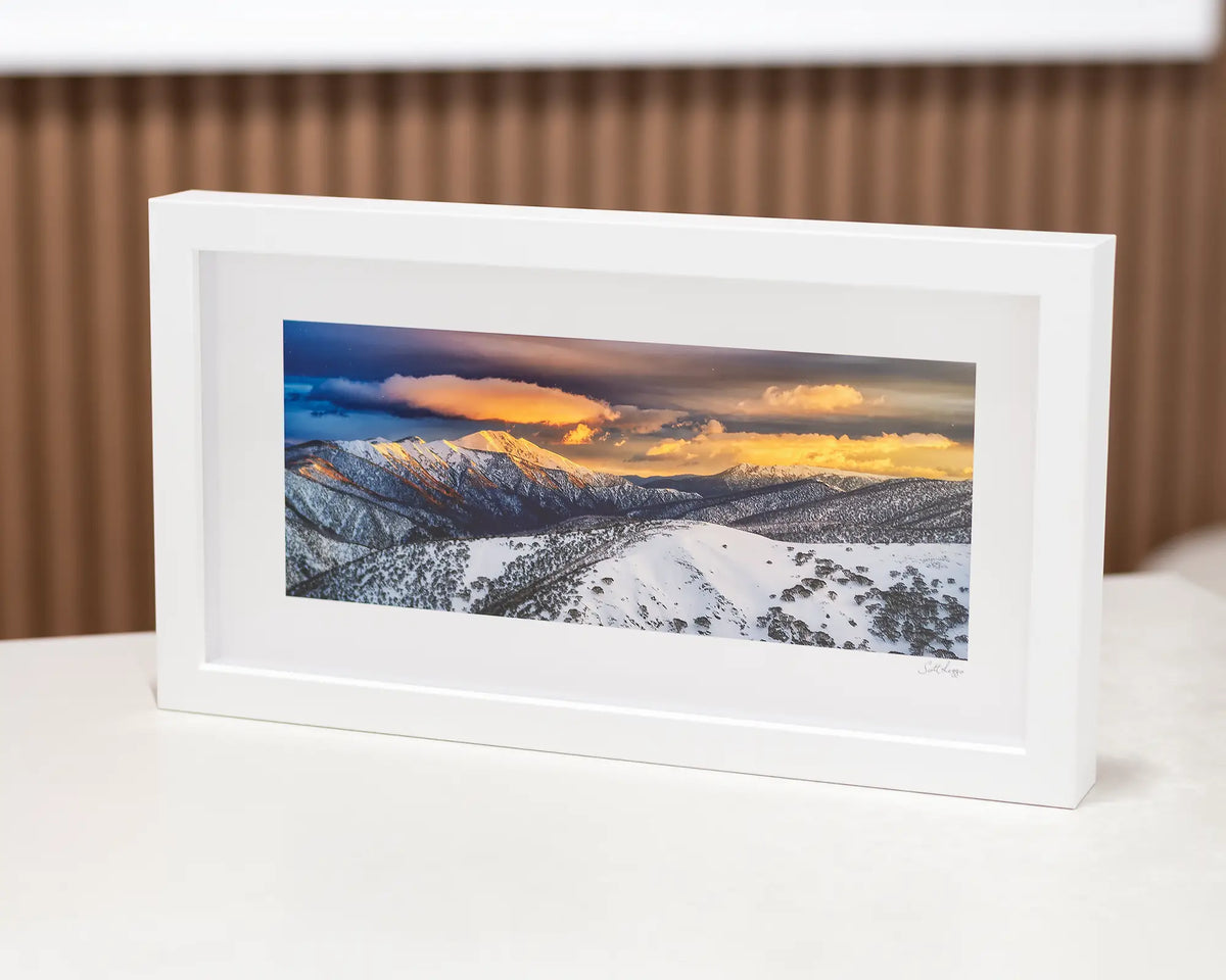 Alpine Magic small framed print with white frame sitting on desk.