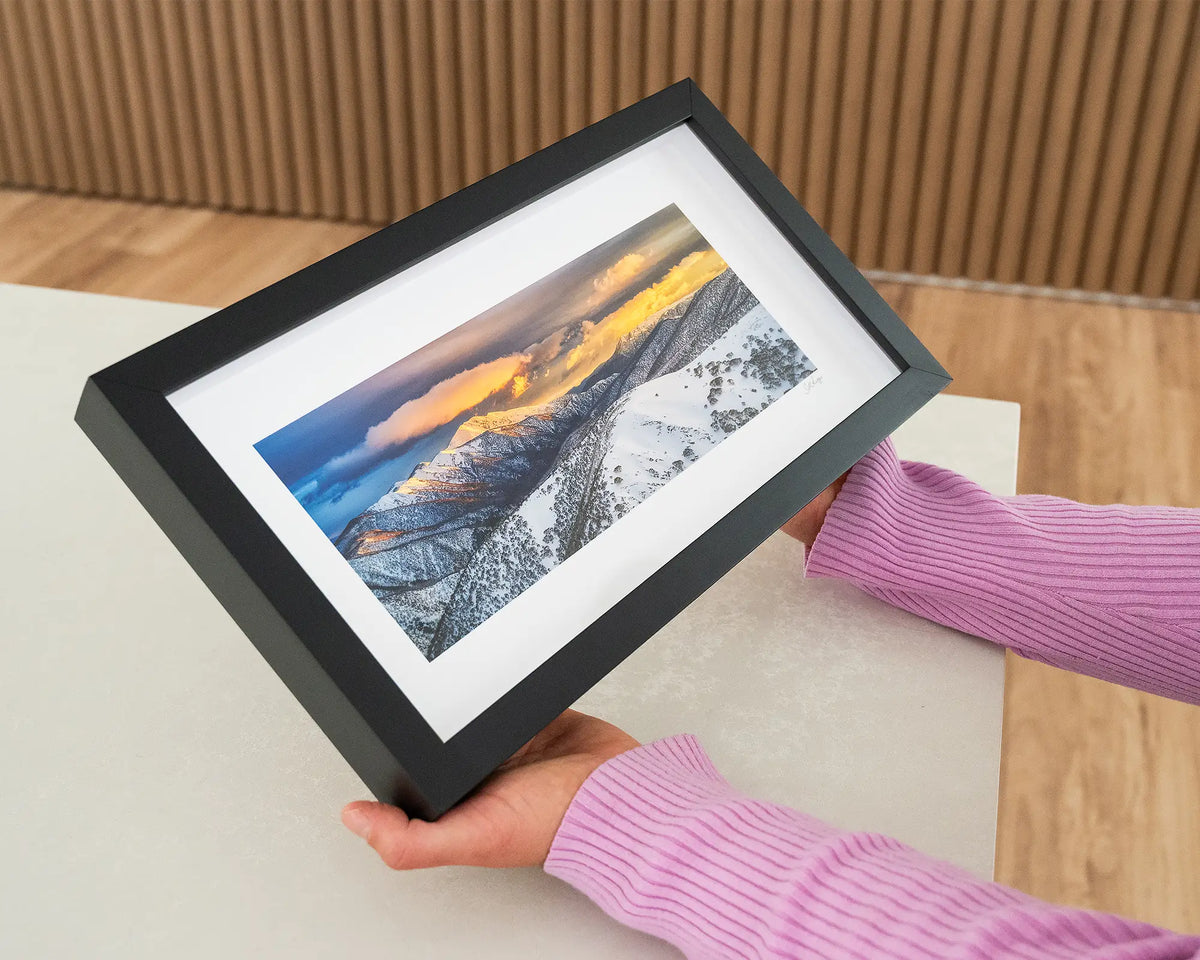 Alpine Magic. Small print with black frame of sunrise over Mount Feathertop, Victoria, held in hands.