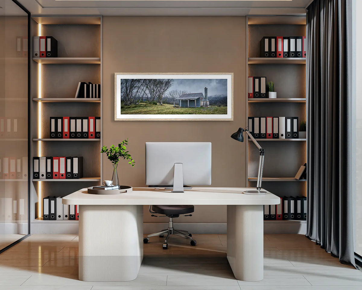 Alpine Retreat. Bradley and O&#39;Briens hut wall art print, with a Tasmanian Oak frame, hung behind an office desk. 