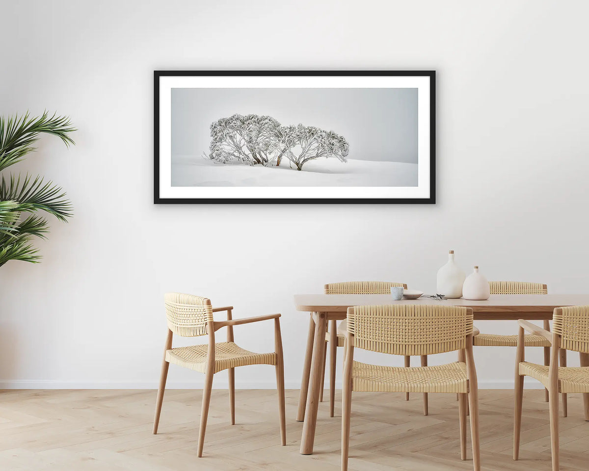 Alpine Spirit. Photographic wall art print with a black frame, of snow gums in snow, hung in a dining room. 