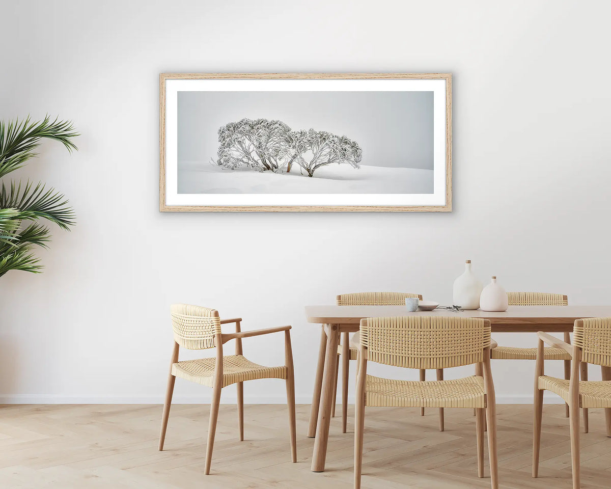 Alpine Spirit. Photographic wall art print with a timber frame, of snow gums in snow, hung in a dining room. 