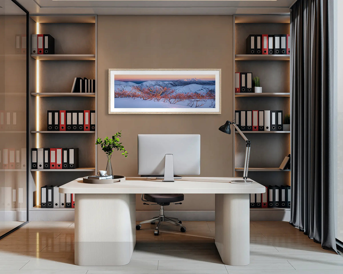 Alpine Sunrise. Wall art print with a Tasmanian Oak frame of a sunrise over the Victorian Alps, hung behind an office desk. 