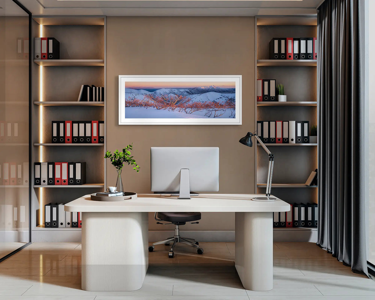 Alpine Sunrise. Wall art print with a white frame of a sunrise over the Victorian Alps, hung behind an office desk. 