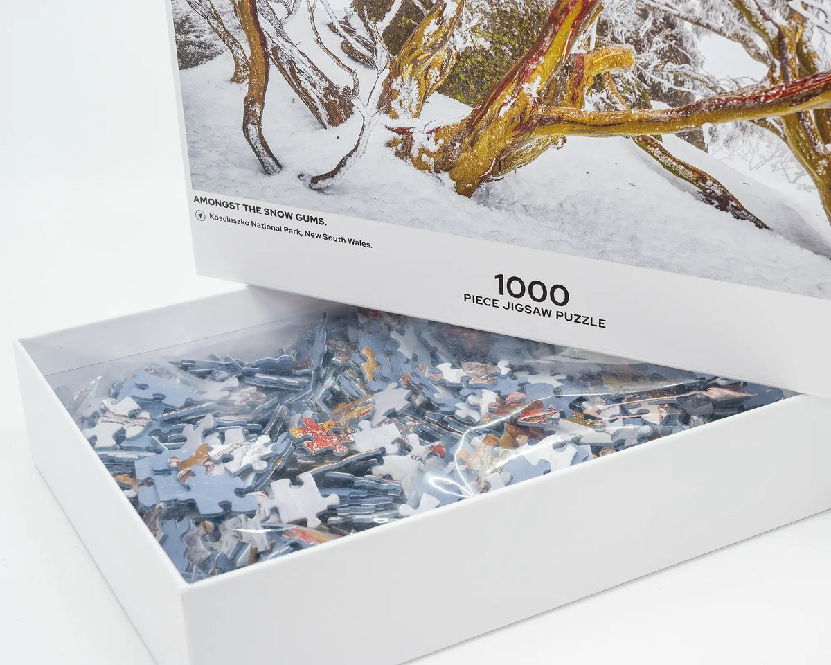 Amongst The Snow Gums. 1000 piece jigsaw puzzle open box showing puzzle pieces of snow covered gum trees.