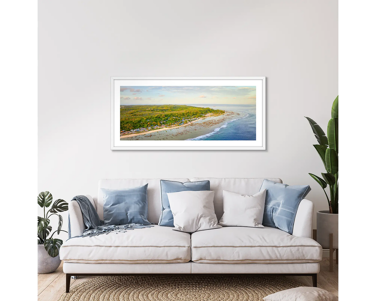 Anetan Awakes. Framed wall art print of Anetan Nauru at sunrise, with a white frame, hung above a couch. 