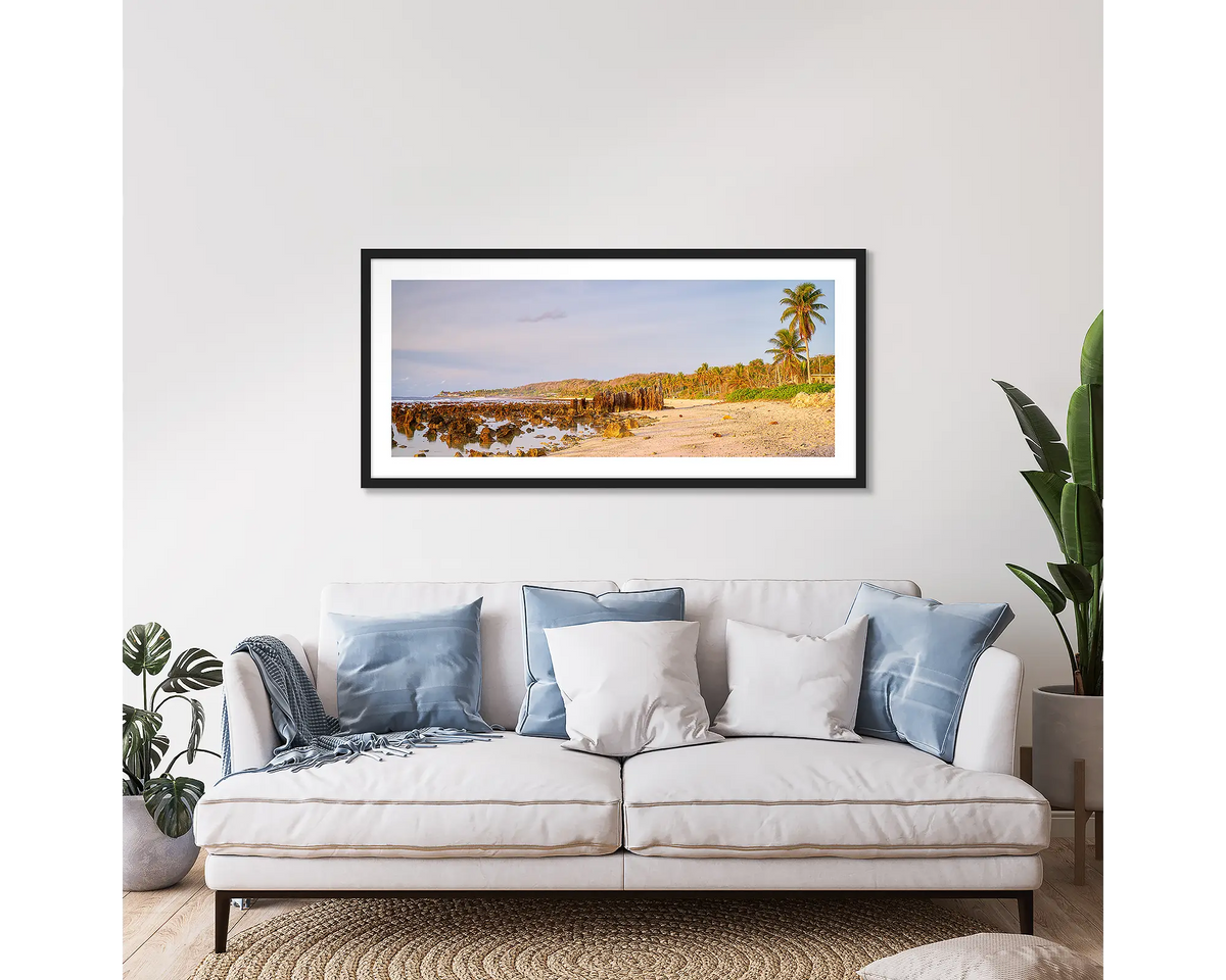 Anibare Rise. Framed wall art print of Anibare beach, Nauru, at sunrise, with a black frame, hung above a couch. 