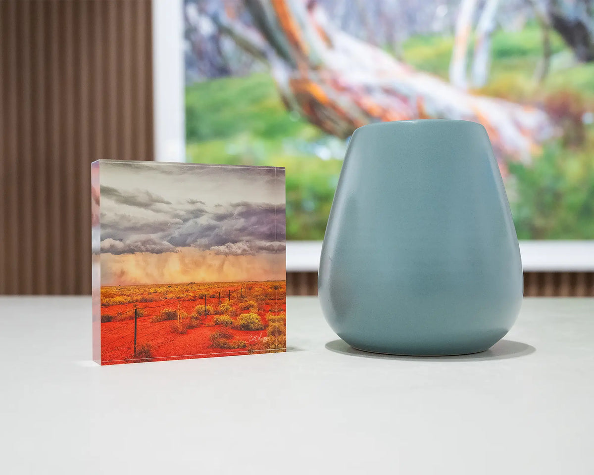 Approaching Storm. Acrylic block of an outback storm, South Australia, on desk styled with a small vase and artwork in background.