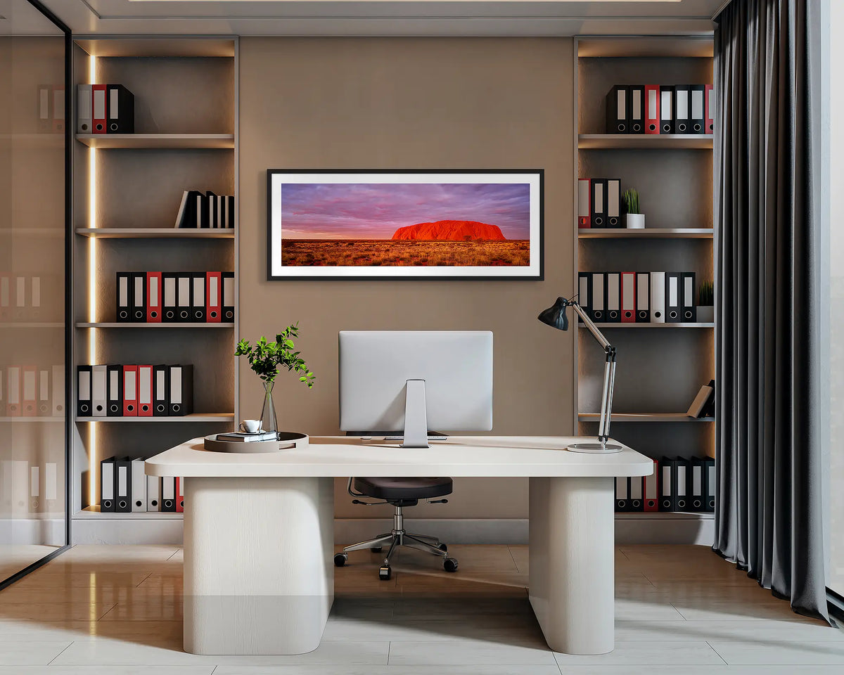 Australian Icon. Uluru sunset, panoramic wall art print with a black frame, hung behind an office desk. 
