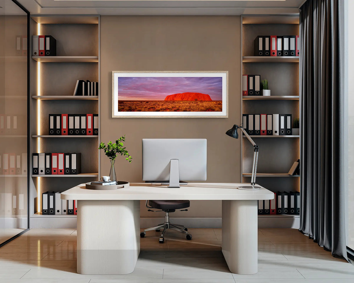 Australian Icon. Uluru sunset, panoramic wall art print with a Tasmanian Oak frame, hung behind an office desk. 