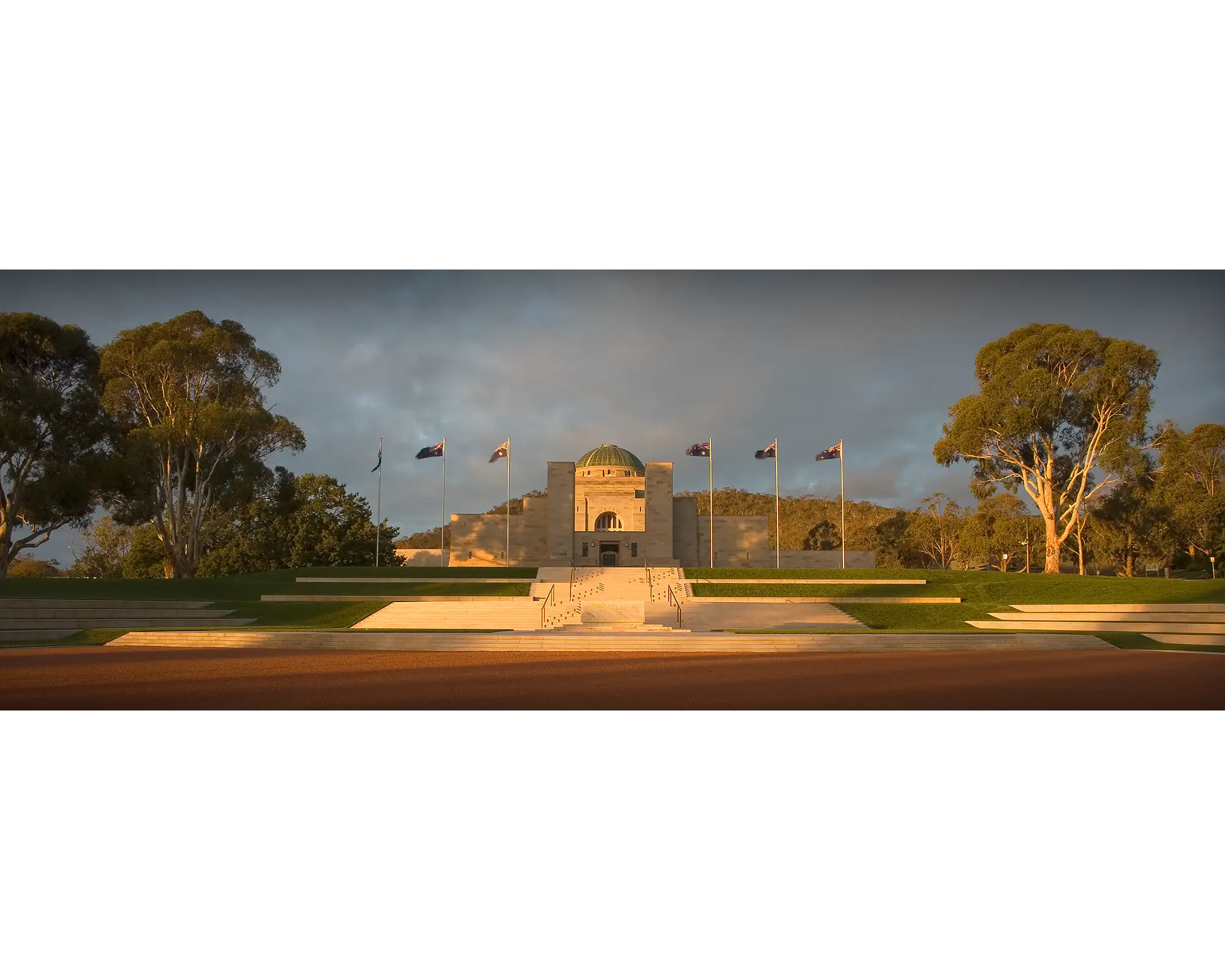 Australian War Memorial surrounded by gum trees at sunset.