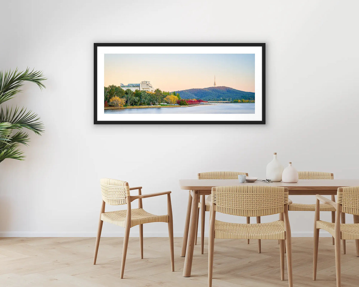 Autumn Arrival. Photographic wall art print with a black frame, of a sunrise over Lake Burley Griffin, hung in a dining room. 