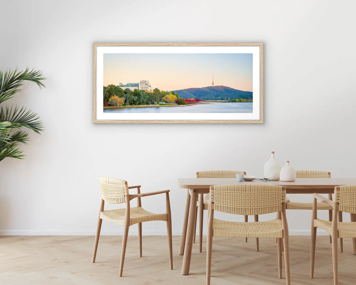 Autumn Arrival. Photographic wall art print with a timber frame, of a sunrise over Lake Burley Griffin, hung in a dining room. 