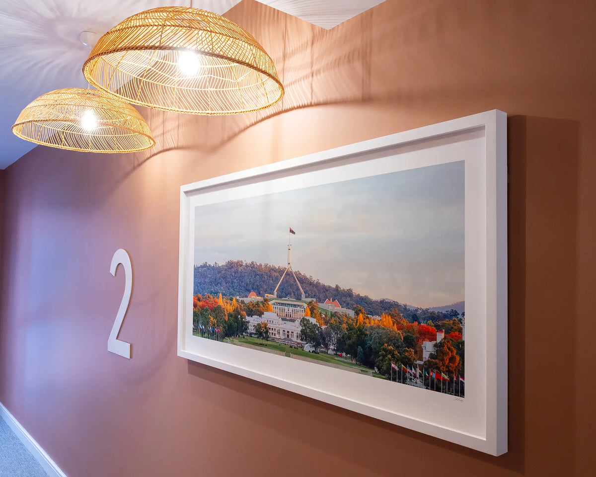 Autumn Bubble. Autumn sunset over Parliament House with white frame hung on terracotta coloured wall, second floor apartment building.