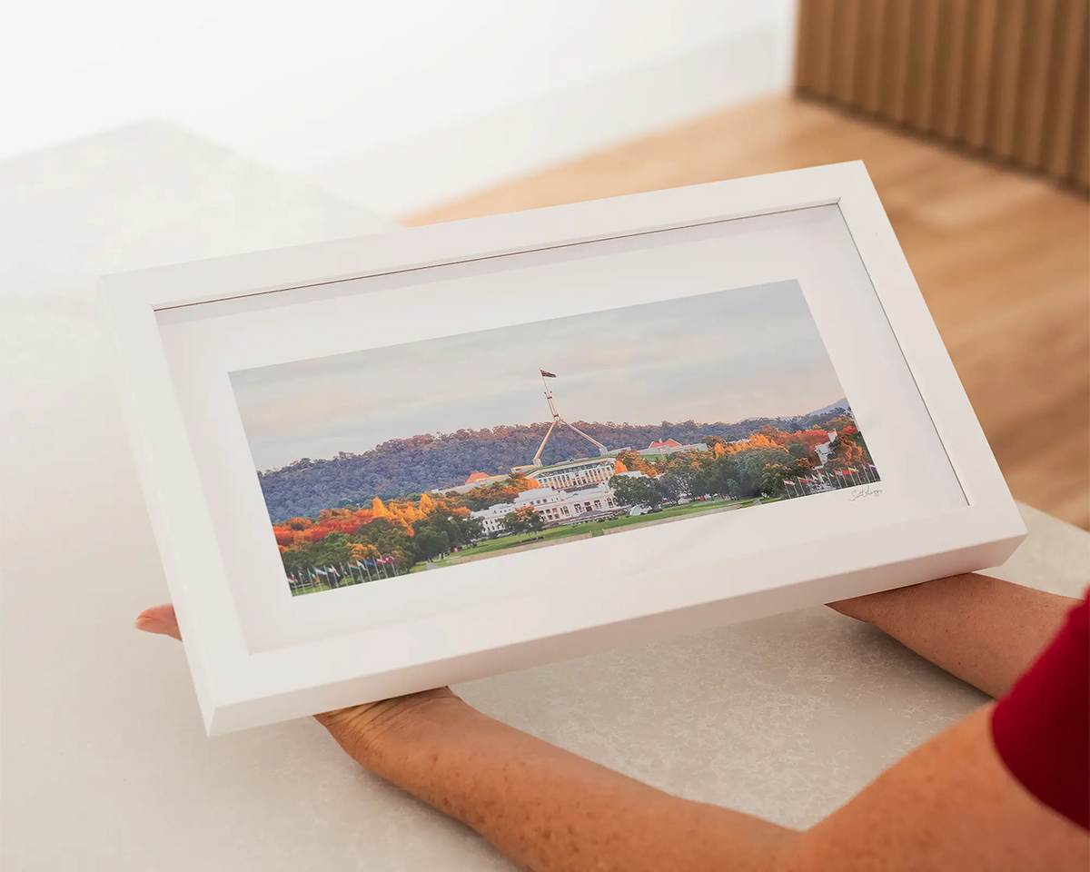 Autumn Bubble. Canberra sunset small frame wall art, with a white frame being held.