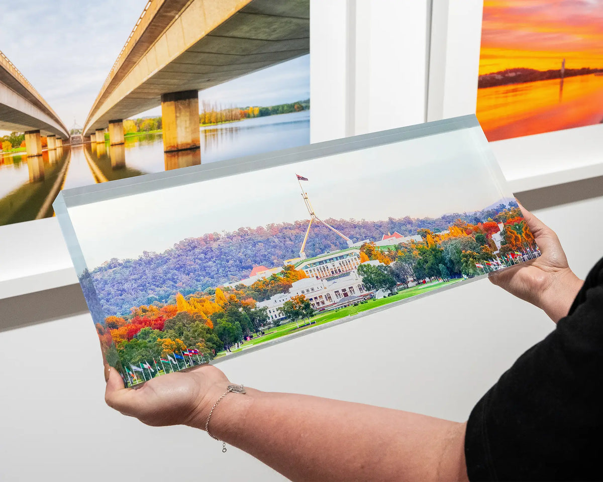Autumn Bubble. Hand held acrylic block of autumn trees surrounding Old and New Parliament House, with Canberra artworks in the background.