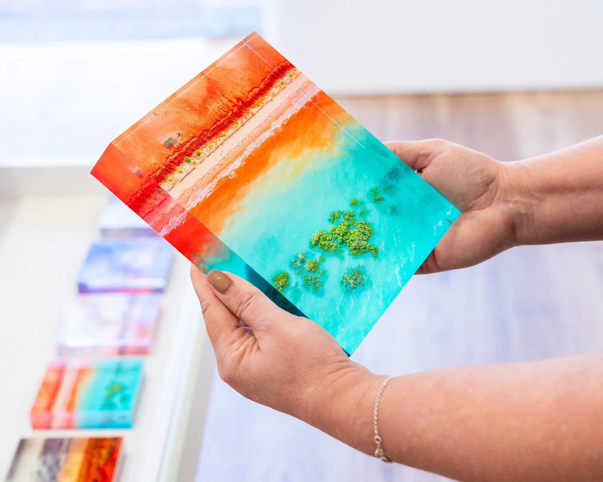 Blend. Acrylic block aerial coastal view of Broome, Western Australia, being held in hands.