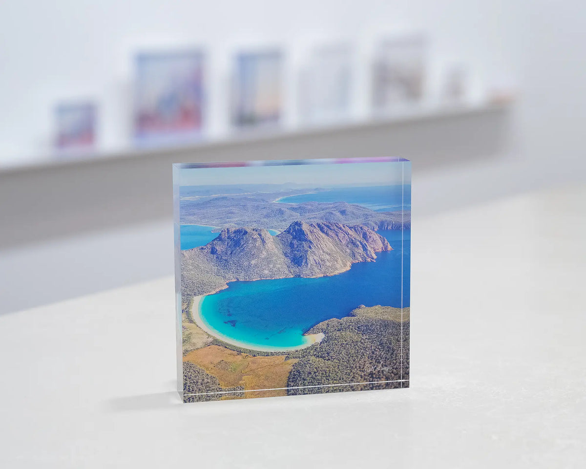 Blue Beauty. Acrylic block aerial view of Wineglass Bay, Tasmania, in gallery with display shelf behind.