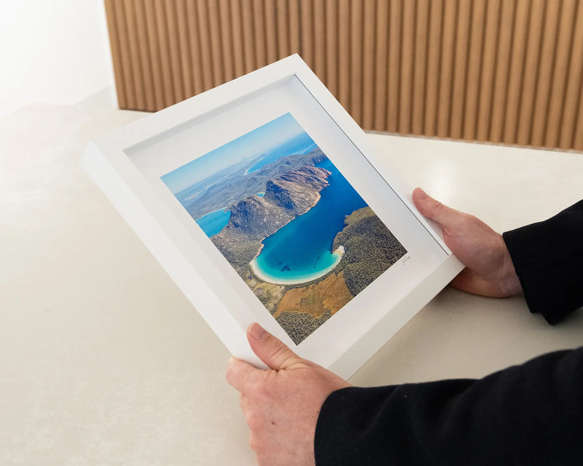 Blue Beauty. Wineglass Bay Freycinet National Park small framed print with white frame being hand held.