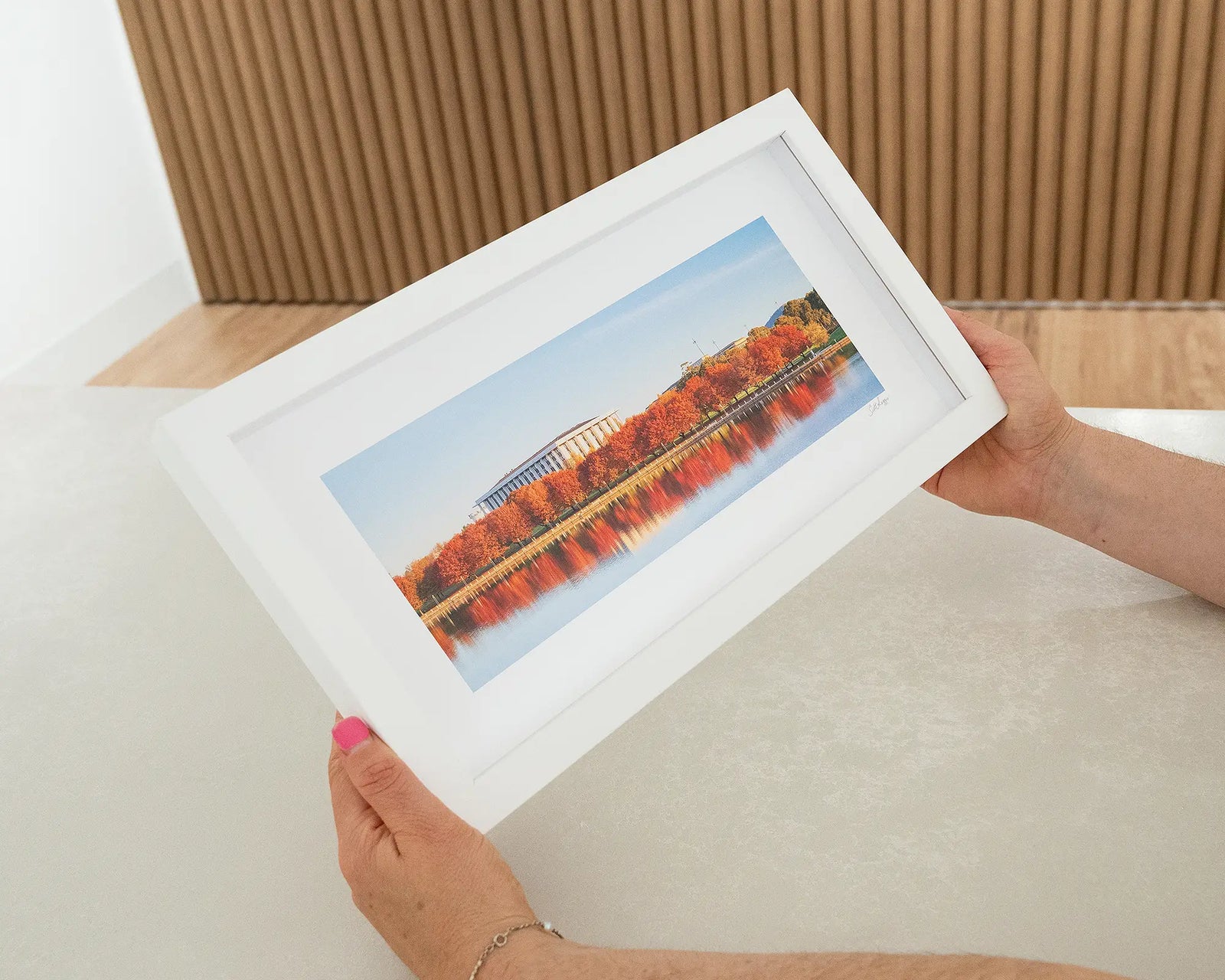 Framed photographic print of trees turning red in autumn, in front of the National Library. 