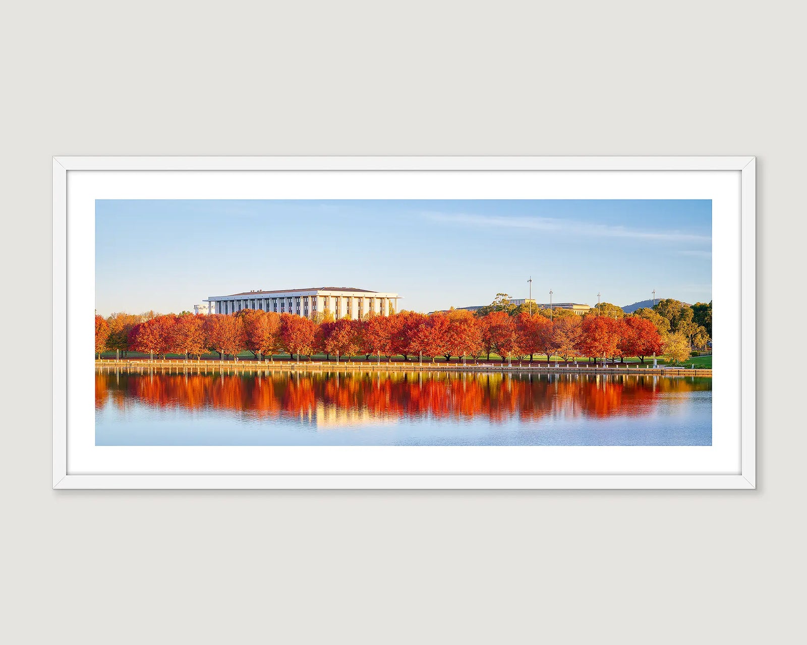 Framed photographic print of trees turning red in autumn, in front of the National Library. 
