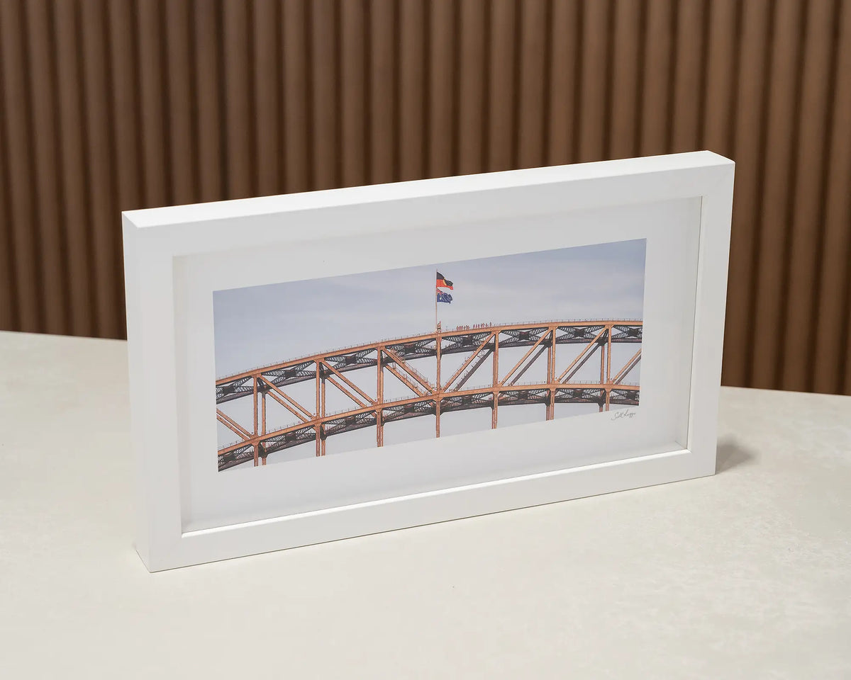 Bridge Climb. People on top of Sydney Harbour Bridge small print with white frame on desk.