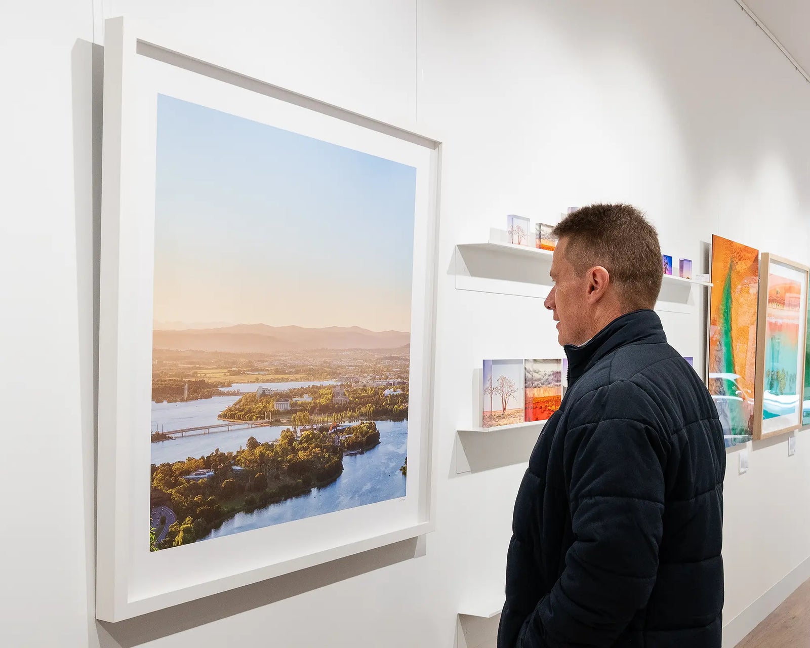 Framed photograph from an aerial perspective of Lake Burley Griffin and Canberra surrounds with a view to the Brindabella Ranges. 