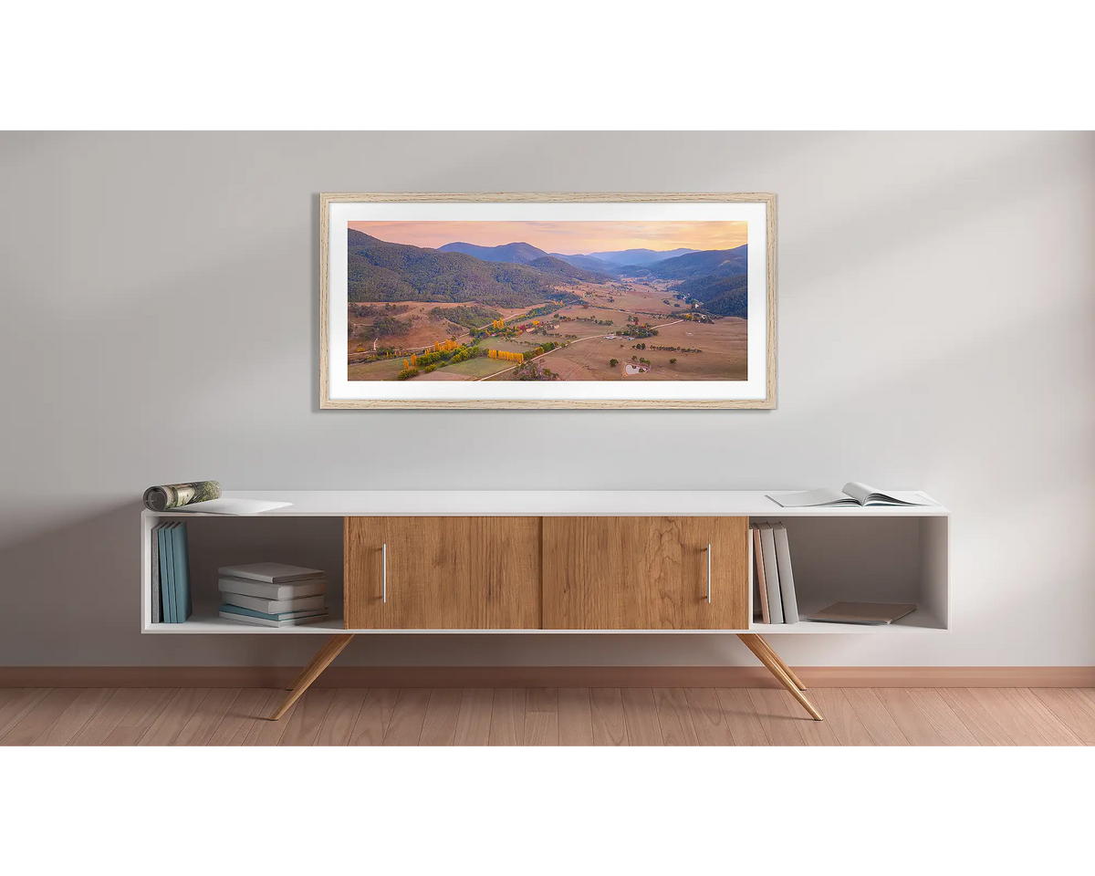 Brindabella Rise. Wall art print with a timber frame, of a sunrise over the Brindabella valley, hung above a side table. 
