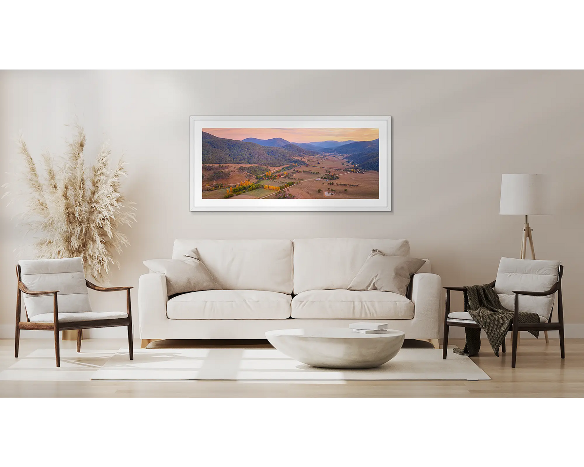 Brindabella Rise. Wall art print with white frame of a sunrise over Brindabella Valley hung above a couch.
