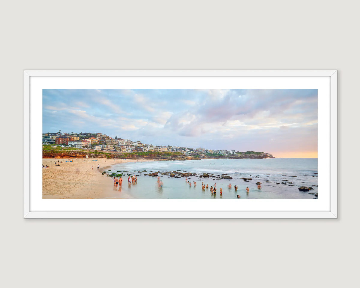 Framed photograph of a coastal scene of people enjoying a morning swim at Bronte Beach. 