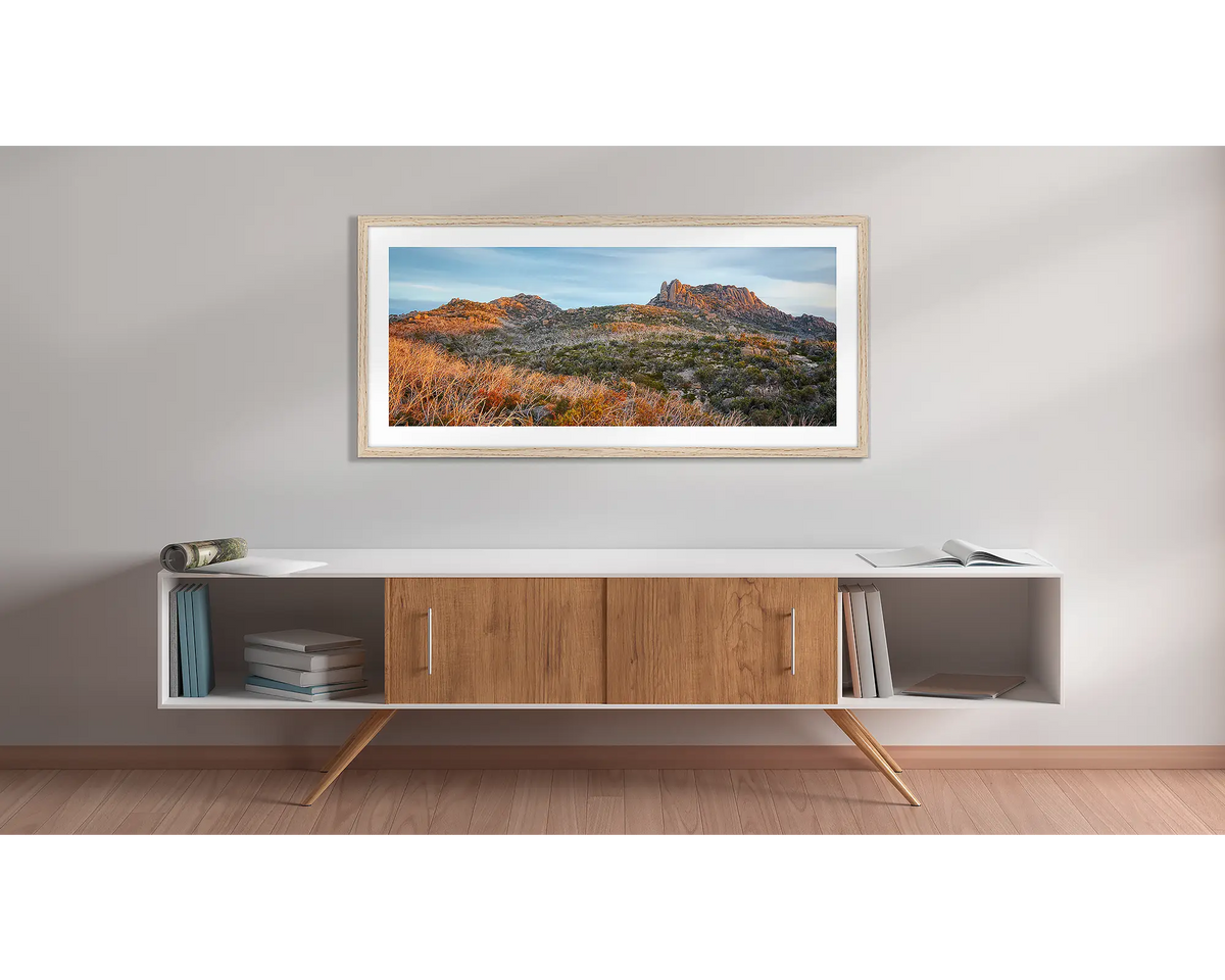 Buffalo Heights. Wall art print with a timber frame, of a sunset over the Cathedral, Mount Buffalo, hung above a side table. 