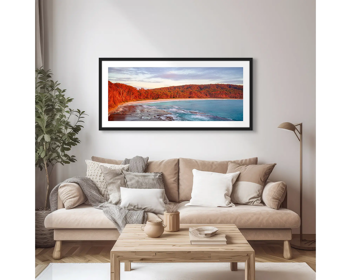 Calm at Depot Beach. Framed wall art print of a sunrise at Depot Beach, South Coast, with a black frame and hung above a couch.