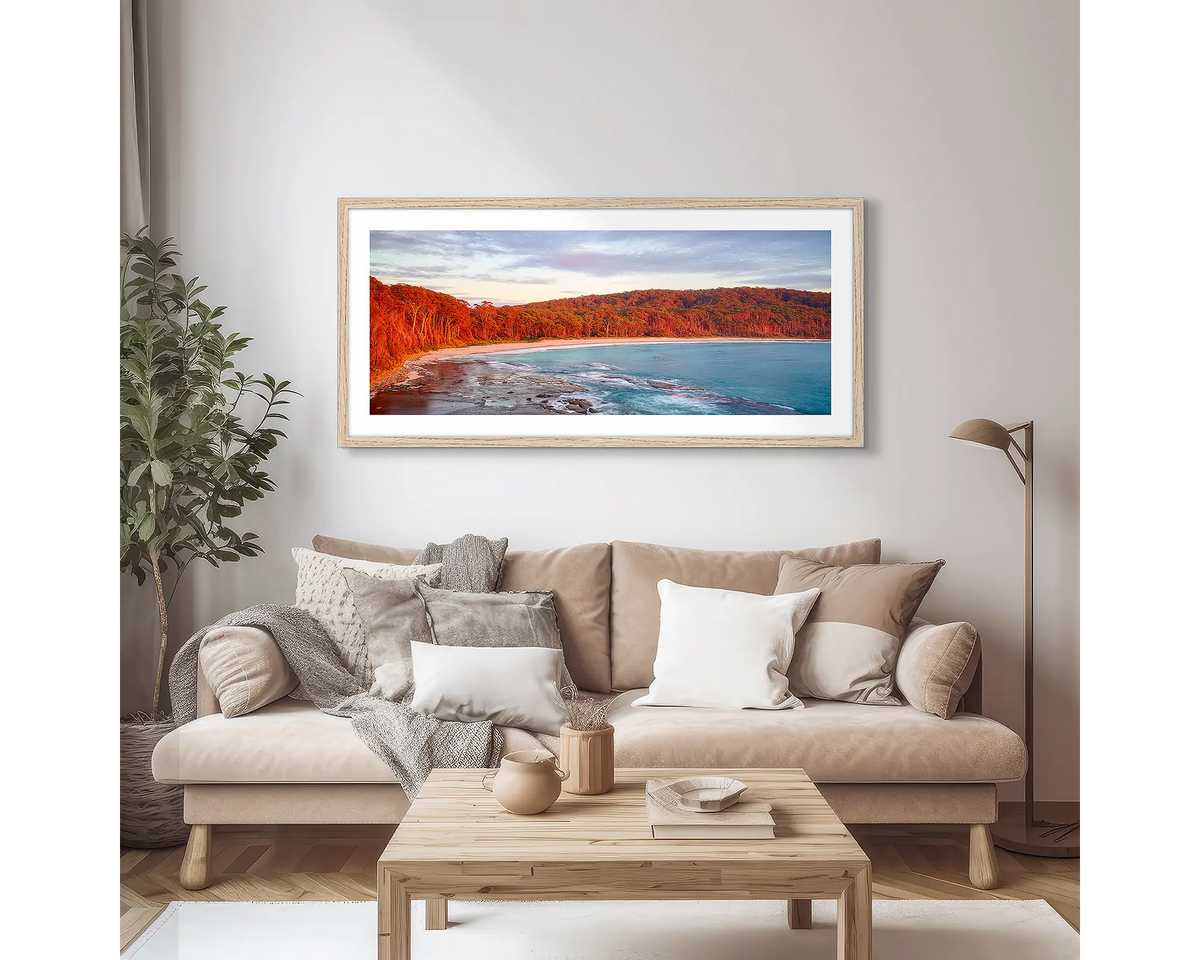 Calm at Depot Beach. Framed wall art print of a sunrise at Depot Beach, South Coast, with a timber frame and hung above a couch. 