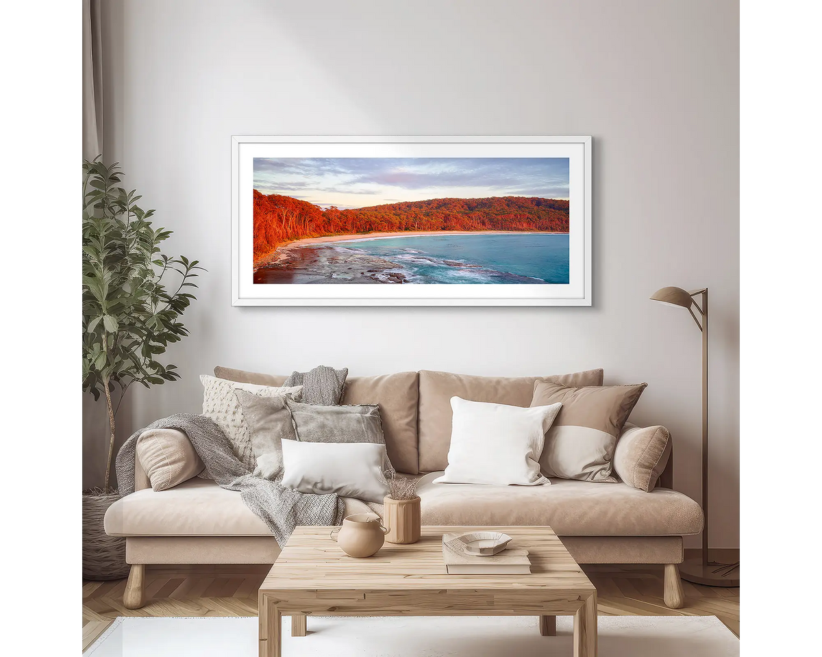 Calm at Depot Beach. Framed wall art print of a sunrise at Depot Beach, South Coast, with a white frame and hung above a couch. 