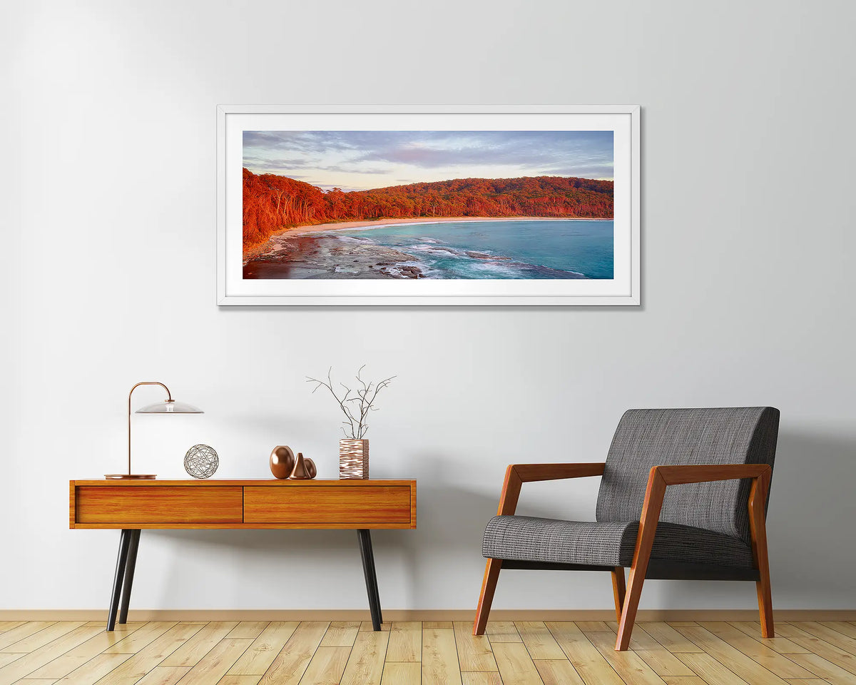 Calm at Depot Beach. Framed wall art print of a sunrise at Depot Beach, South Coast, with a white frame and hung above a side table.
