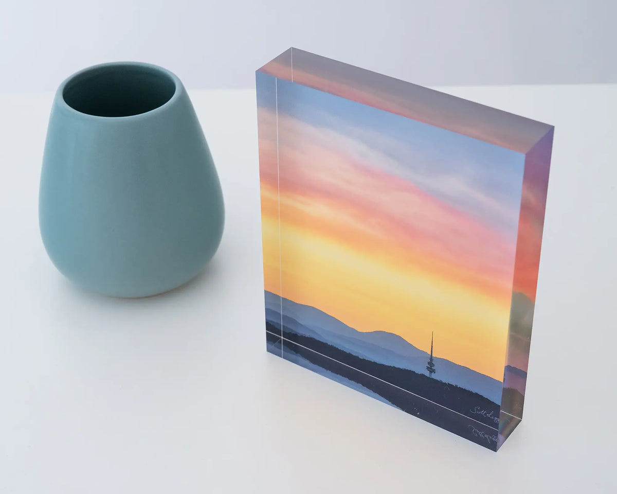 Canberra Beacon. Acrylic block of sunset over Black Mountain Tower, top side view, styled with a small vase.