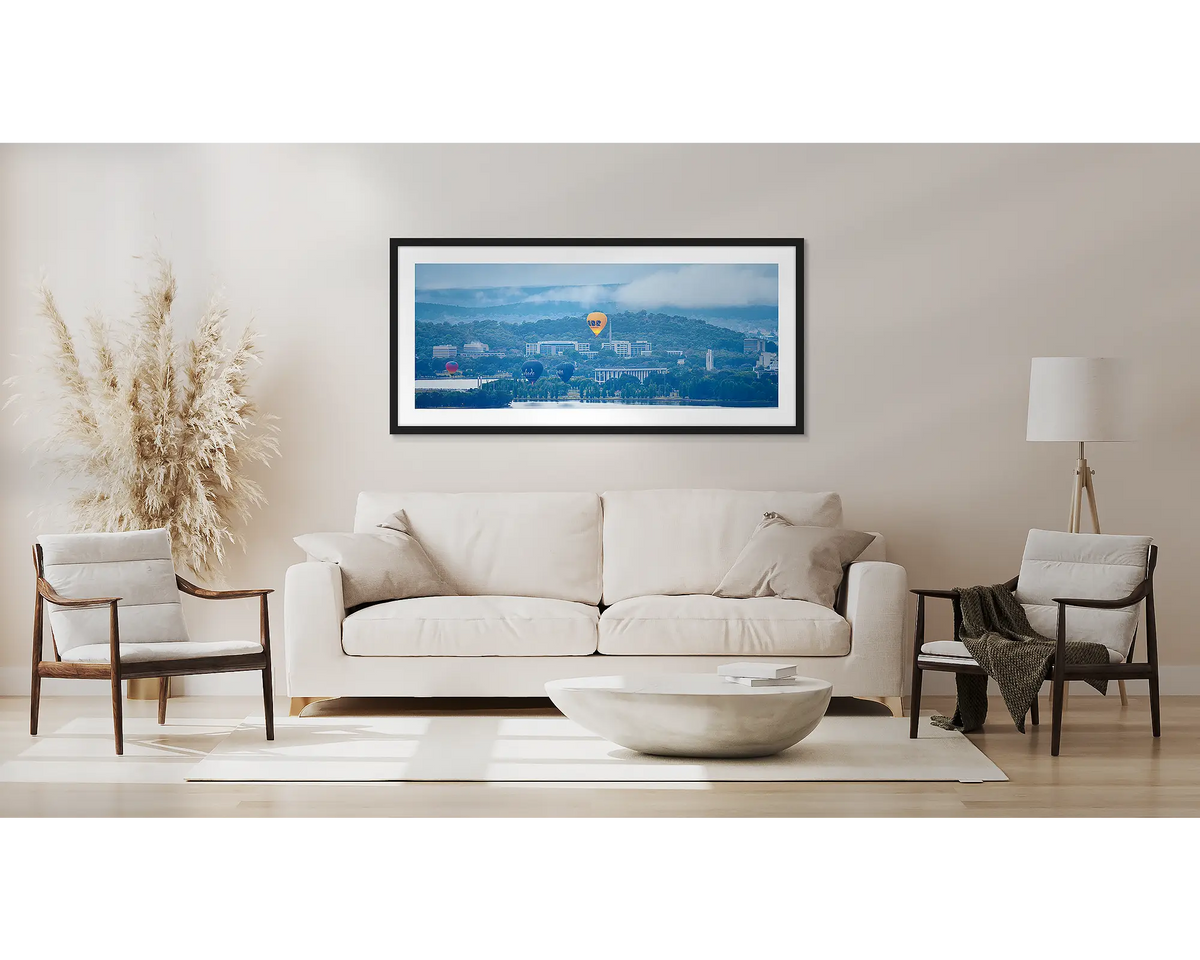 Canberra Rising. Hot air balloons over Canberra, wall art with a black frame, above a couch. 