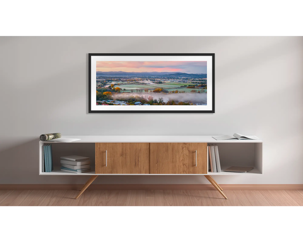 Canturf. Wall art print with a black frame, of a sunrise over Canturf, Fyshwick, Canberra, hung above a side table. 