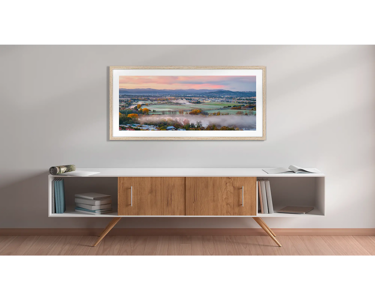 Canturf. Wall art print with a timber frame, of a sunrise over Canturf, Fyshwick, Canberra, hung above a side table. 