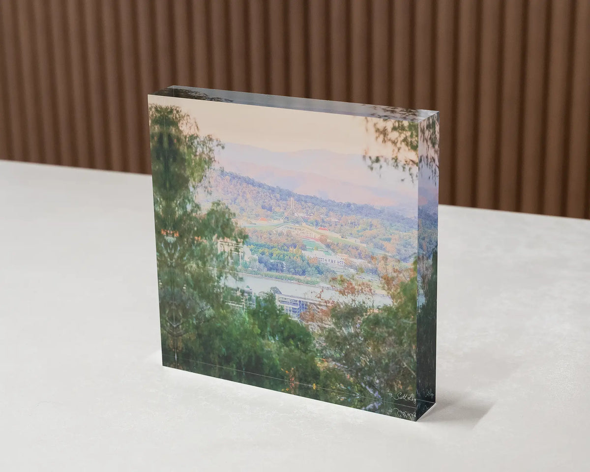 Capital View. Acrylic block of Parliament House views through gum trees, sitting on a desk.