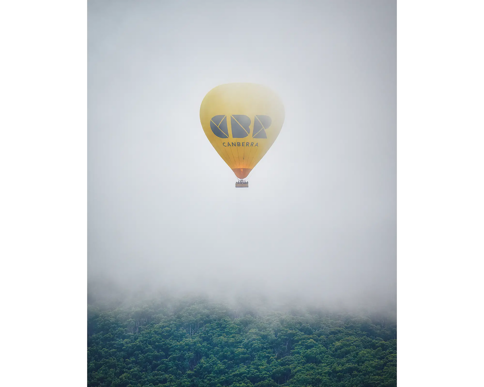 CBR Balloon. Visit Canberra hot air balloon emerging from fog over Black Mountain, during the Canberra balloon festival.